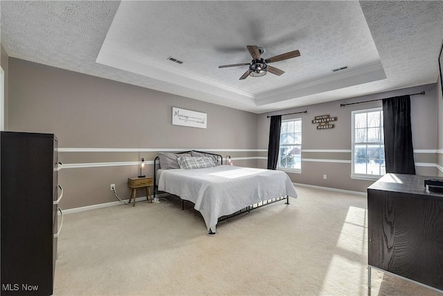 carpeted bedroom featuring ornamental molding, a textured ceiling, ceiling fan, and a tray ceiling