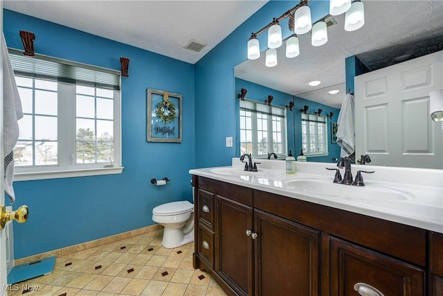 bathroom featuring vanity, a healthy amount of sunlight, tile patterned floors, and toilet