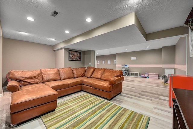 living room with a textured ceiling and light hardwood / wood-style flooring