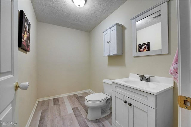 bathroom featuring vanity, hardwood / wood-style floors, a textured ceiling, and toilet