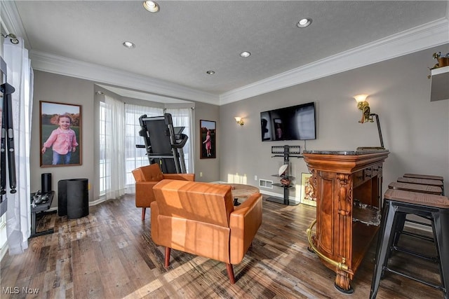 living room featuring wood-type flooring, ornamental molding, and a textured ceiling