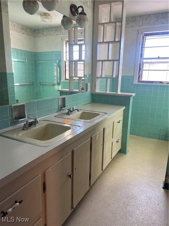 bathroom with vanity, a healthy amount of sunlight, and tile walls