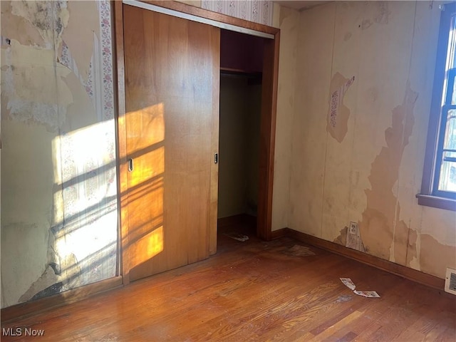 unfurnished bedroom featuring wood-type flooring and a closet