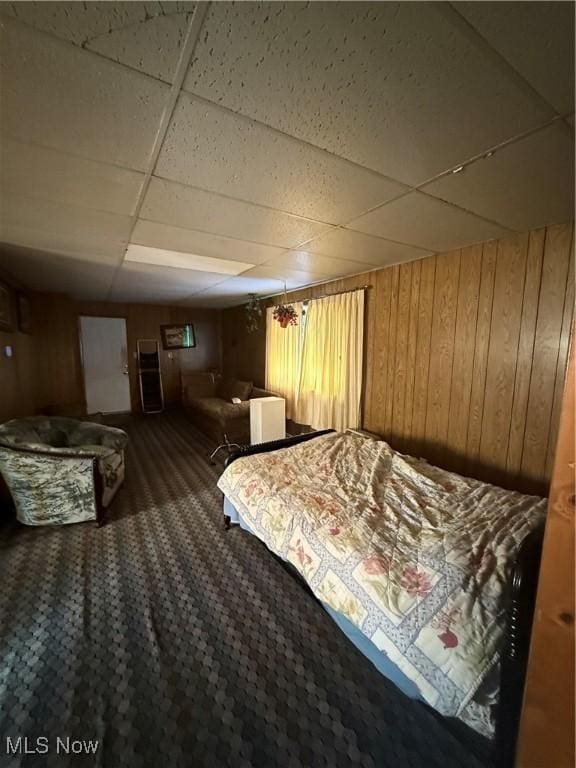 bedroom with wooden walls and a drop ceiling