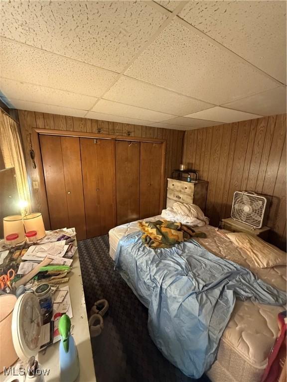 bedroom featuring wood walls and a drop ceiling