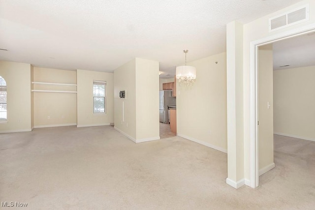 empty room with light carpet and an inviting chandelier