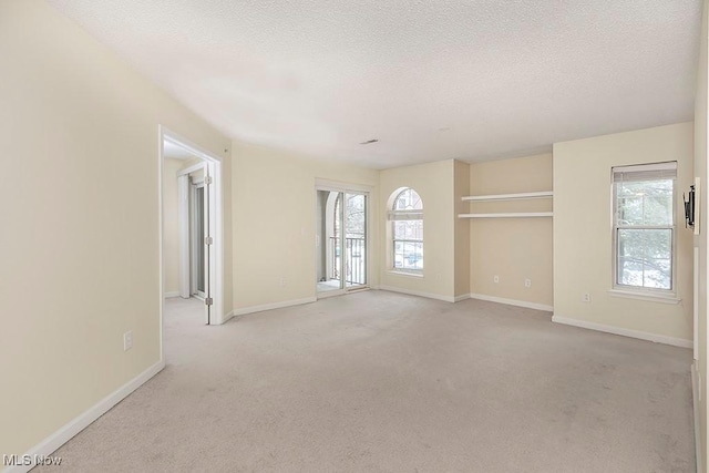 unfurnished room featuring light carpet and a textured ceiling