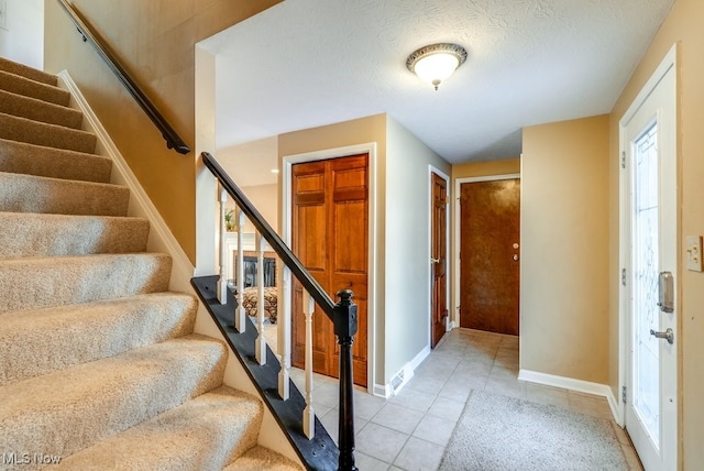 stairs with tile patterned floors and a textured ceiling