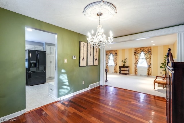 dining room featuring a textured ceiling, a chandelier, and light hardwood / wood-style flooring