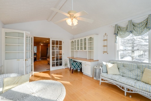 sitting room with french doors, a textured ceiling, light hardwood / wood-style flooring, and vaulted ceiling with beams