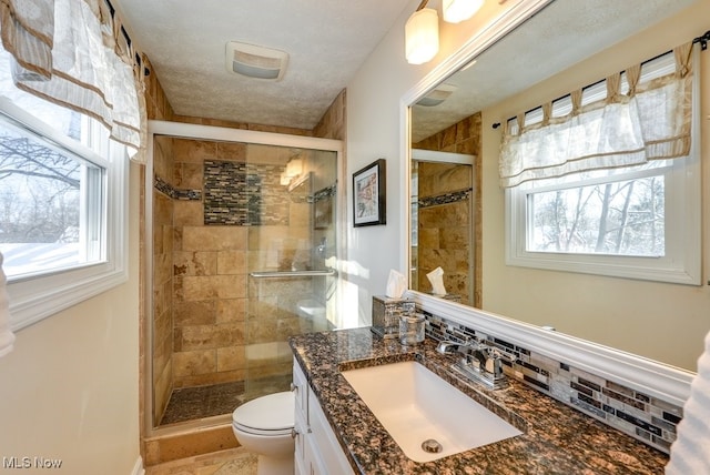 bathroom featuring plenty of natural light, toilet, an enclosed shower, and backsplash