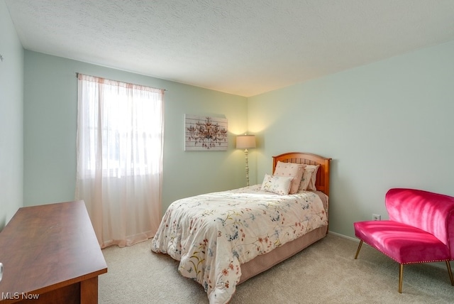 bedroom featuring light colored carpet and a textured ceiling