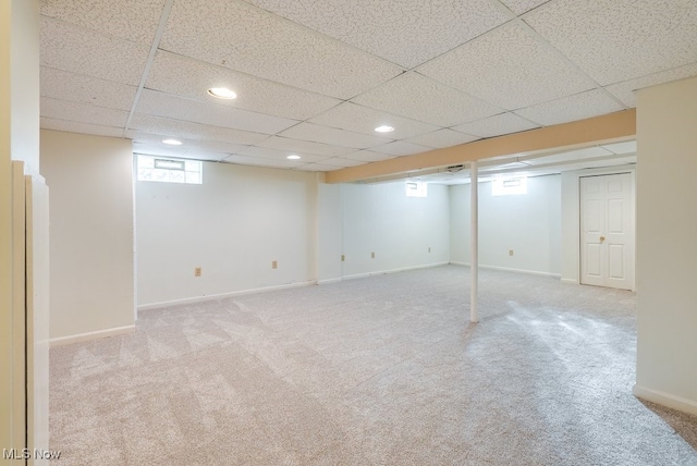 basement featuring a drop ceiling and light colored carpet