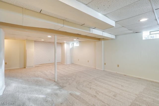 basement featuring a paneled ceiling and carpet flooring