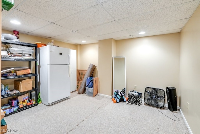 interior space with a drop ceiling, carpet flooring, and white refrigerator