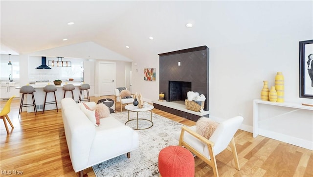 living room with a premium fireplace, lofted ceiling, sink, and light hardwood / wood-style floors