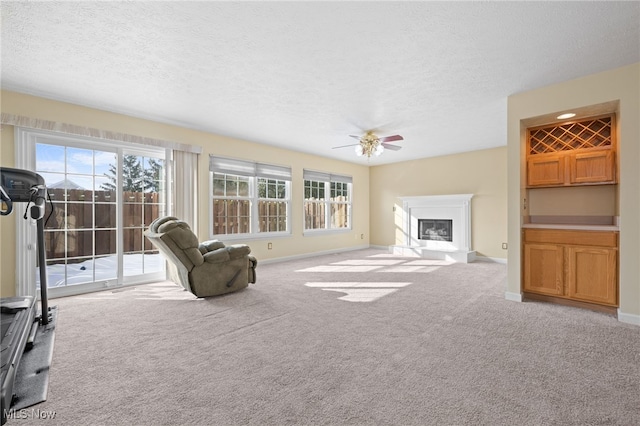 unfurnished living room with ceiling fan, light colored carpet, and a textured ceiling