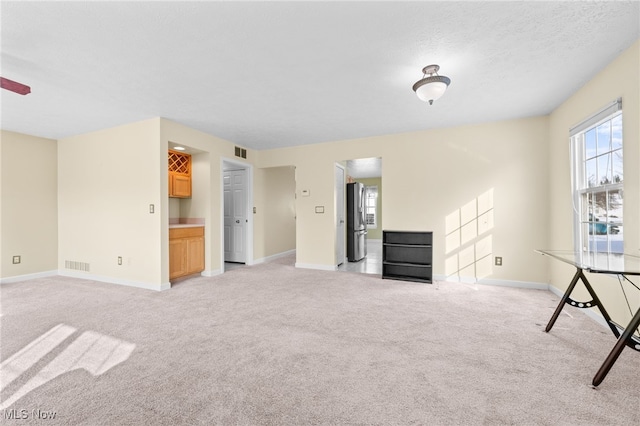 unfurnished living room with light carpet and a textured ceiling