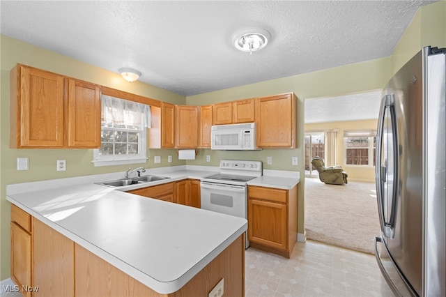 kitchen featuring sink, light colored carpet, white appliances, kitchen peninsula, and a textured ceiling