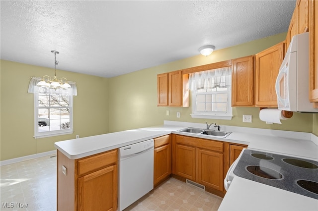 kitchen with sink, white appliances, a textured ceiling, decorative light fixtures, and kitchen peninsula