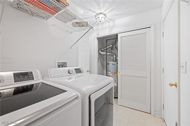 laundry area featuring water heater, light tile patterned flooring, separate washer and dryer, and a textured ceiling