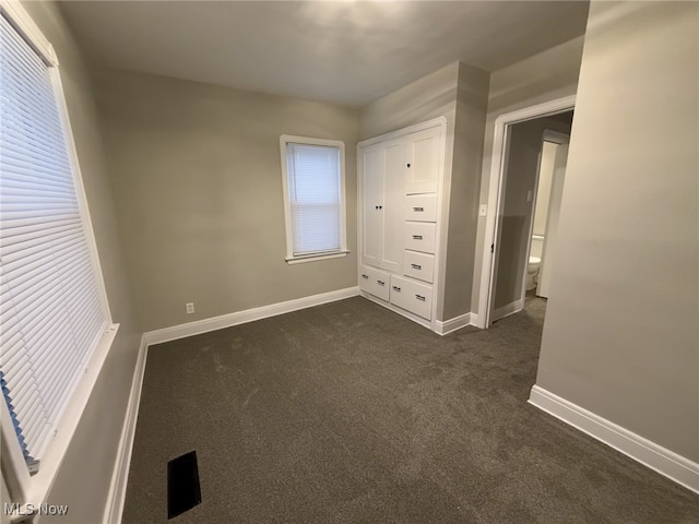 unfurnished bedroom with dark carpet