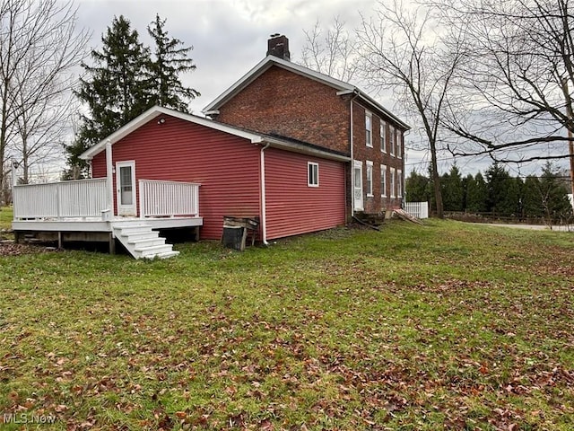 back of property featuring a wooden deck and a lawn