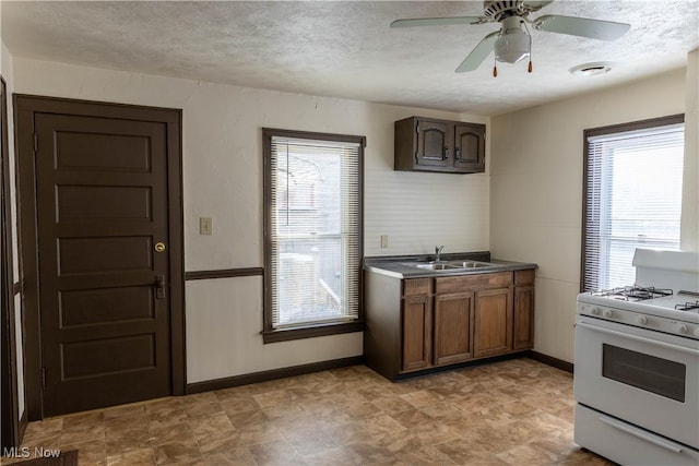 kitchen featuring sink, ceiling fan, gas range gas stove, dark brown cabinets, and a textured ceiling