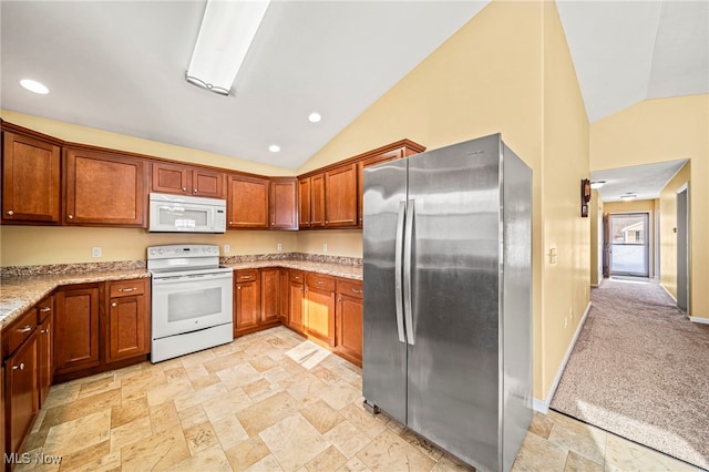 kitchen featuring lofted ceiling, light stone counters, light colored carpet, and white appliances