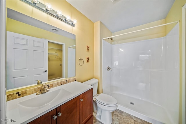 bathroom with a shower, vanity, and toilet