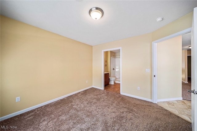 unfurnished bedroom featuring ensuite bathroom and carpet flooring