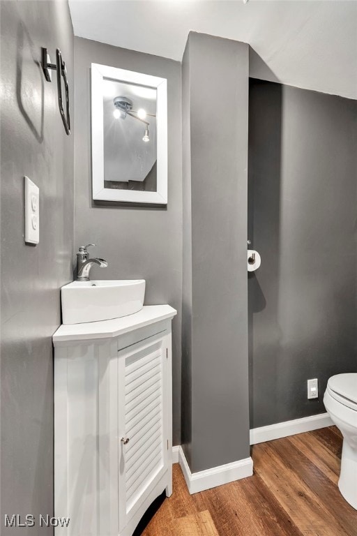 bathroom with wood-type flooring, toilet, and vanity