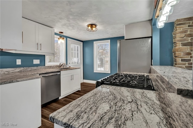 kitchen featuring white cabinetry, appliances with stainless steel finishes, light stone countertops, and sink