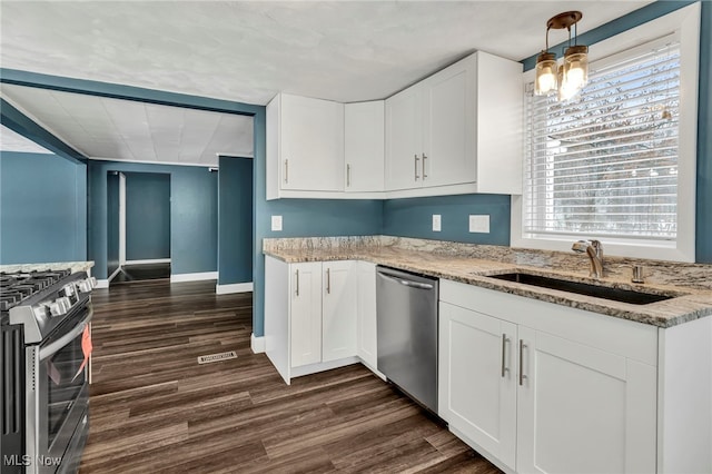 kitchen featuring decorative light fixtures, sink, white cabinets, stainless steel appliances, and light stone countertops