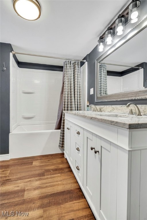 bathroom with hardwood / wood-style flooring, vanity, and shower / bathtub combination with curtain