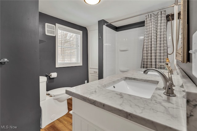 bathroom with wood-type flooring, a shower with shower curtain, vanity, and toilet