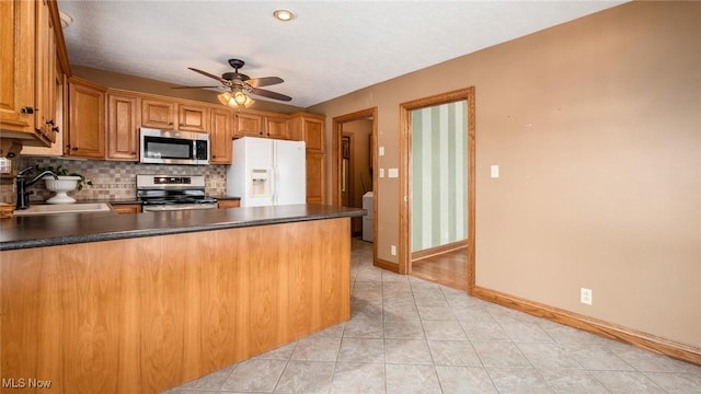 kitchen featuring sink, kitchen peninsula, ceiling fan, stainless steel appliances, and backsplash