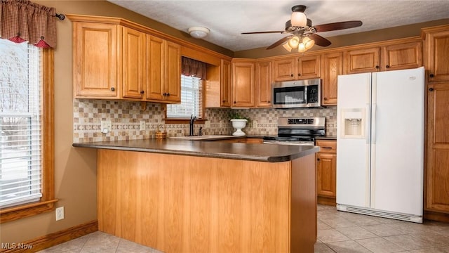 kitchen with stainless steel appliances, kitchen peninsula, sink, and light tile patterned floors