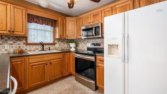 kitchen with appliances with stainless steel finishes, sink, decorative backsplash, light tile patterned floors, and ceiling fan