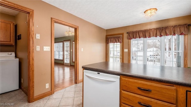 kitchen with washer / clothes dryer, light tile patterned floors, a textured ceiling, and white dishwasher