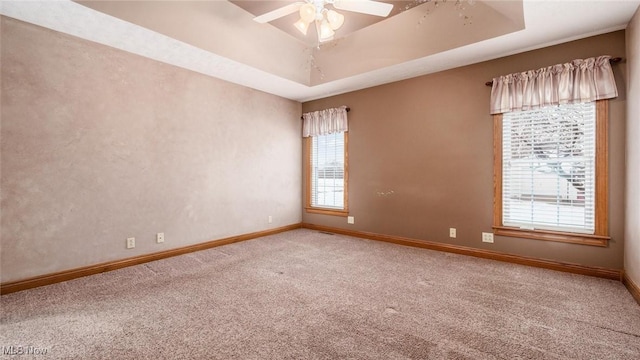 spare room featuring ceiling fan, carpet flooring, and a tray ceiling