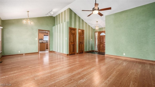 spare room featuring high vaulted ceiling, ceiling fan with notable chandelier, track lighting, and light hardwood / wood-style floors