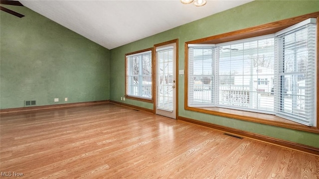 unfurnished room with vaulted ceiling, a wealth of natural light, and light wood-type flooring