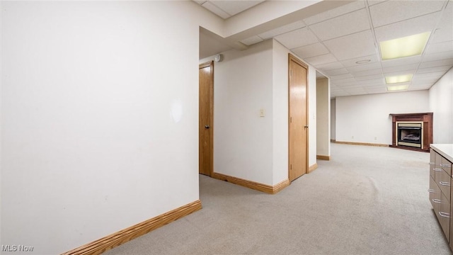 corridor with a paneled ceiling and light carpet