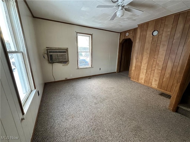 carpeted spare room featuring crown molding, an AC wall unit, ceiling fan, and wood walls