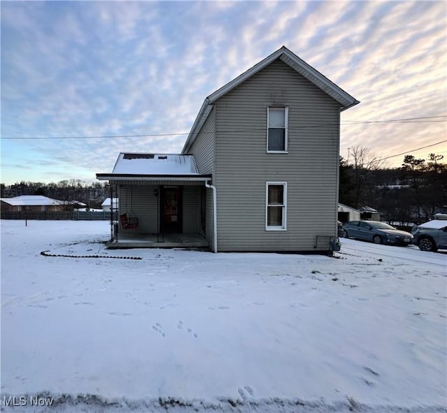 snow covered house featuring covered porch