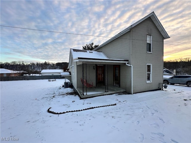 snow covered house featuring cooling unit