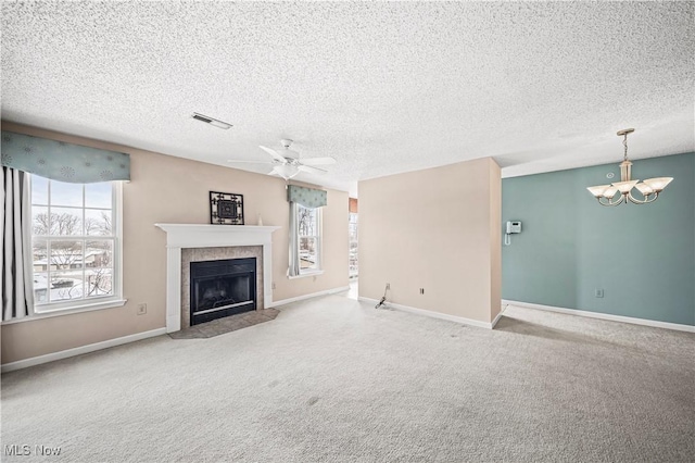 unfurnished living room with a tiled fireplace, ceiling fan with notable chandelier, plenty of natural light, and a textured ceiling