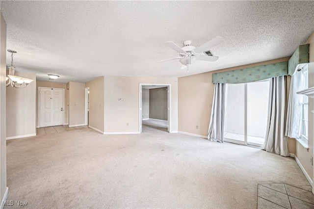 carpeted spare room featuring ceiling fan with notable chandelier and a textured ceiling