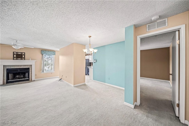 unfurnished living room with ceiling fan with notable chandelier, a fireplace, light colored carpet, and a textured ceiling